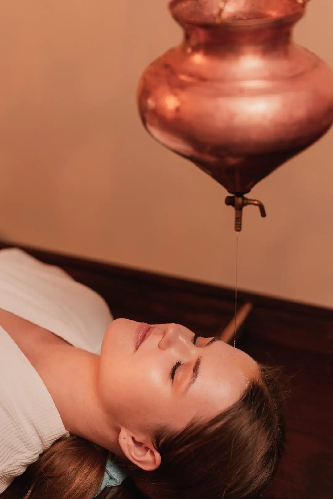 Copper vessel positioned above a guest during an Ayurvedic oil treatment