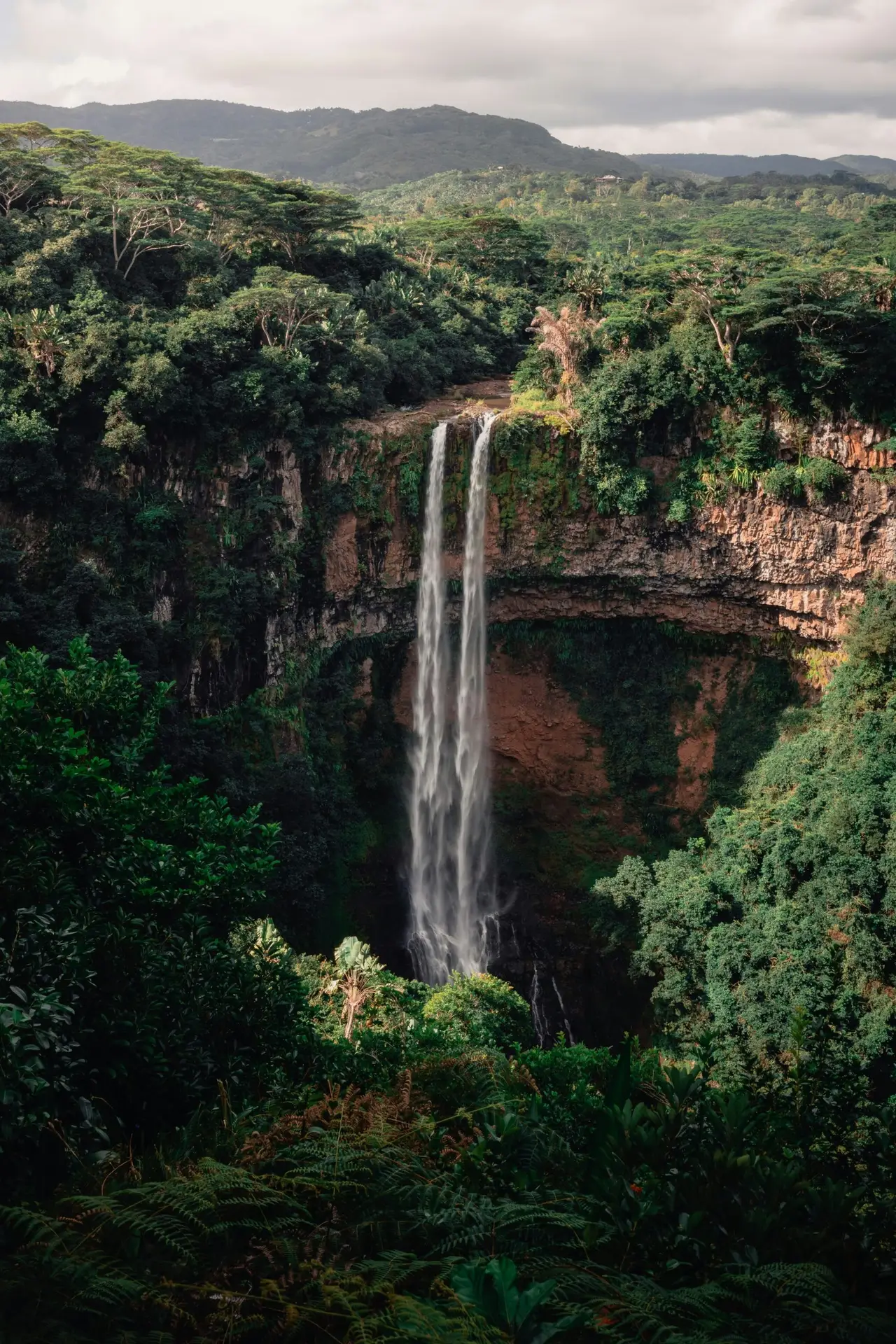 Waterfall flowing through a forested gorge in Mauritius